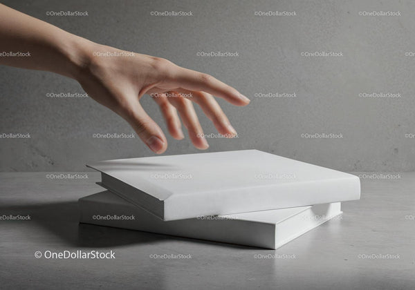 Hand reaching for blank white books on gray surface JPG Mockup Image