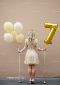 Woman holding balloons with number seven on neutral wall