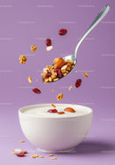 Spoon with granola and almonds over yogurt bowl