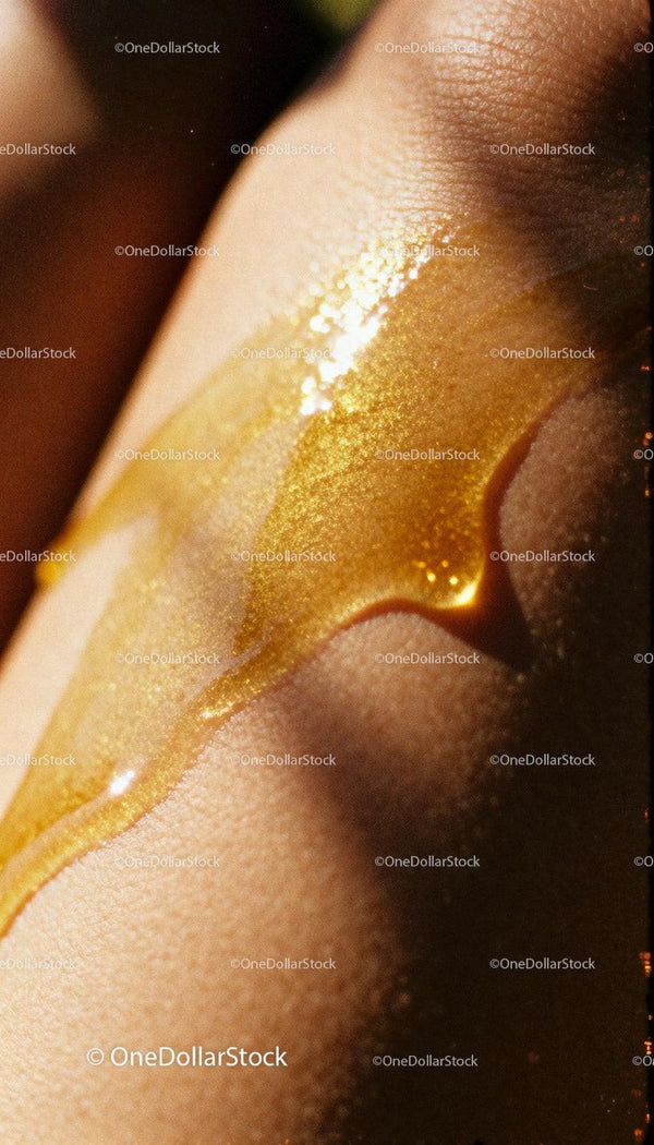Closeup of Golden Honey Dripped on Smooth Skin