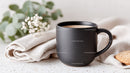 Black Ceramic Coffee Mug on Marble Counter with Flowers and Cookies