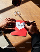 Man writing romantic love note on red card