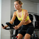 Determined Woman on Exercise Bike in Yellow Sportswear