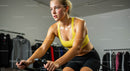Focused Woman in Yellow Top Exercising on Indoor Bike
