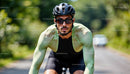 Focused Cyclist in Green Jersey Riding on a Sunlit Road