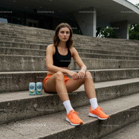 Young Woman Resting on Concrete Steps in Orange Sportswear