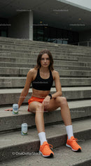 Sporty Woman in Orange Shorts Sitting on Urban Stairs