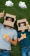 Father and Child Playing in Cardboard Helmets on Grass
