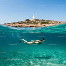 Snorkeler Beneath Turquoise Waves by Coastal Lighthouse