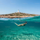 Snorkeling in Clear Waters Near a Coastal Lighthouse