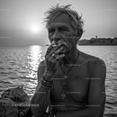 Contemplative Older Man Smoking by the Ocean at Sunset