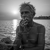 Contemplative Older Man Smoking by the Ocean at Sunset
