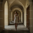 Elegant Woman in White Dress in Arched Hallway