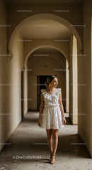 Stylish Woman in White Dress Walking Through Stone Corridor