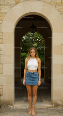 Young Woman in Denim Skirt Under Stone Archway
