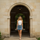 Woman in White Top and Denim Skirt Stands Under Archway