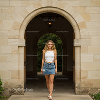 Woman in White Top and Denim Skirt Stands Under Archway