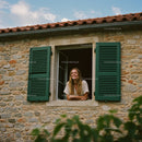 Smiling Woman Leaning Out Stone House Window
