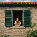 Smiling Woman Leaning Out of Green-Shuttered Window on Stone Wall