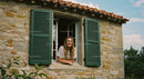 Woman Smiling Through Open Window of Rustic Stone House