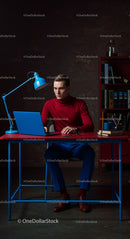 Focused Man in Red Turtleneck Working at Blue Desk