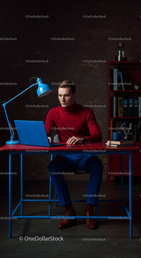 Focused Man in Red Turtleneck Working at Blue Desk