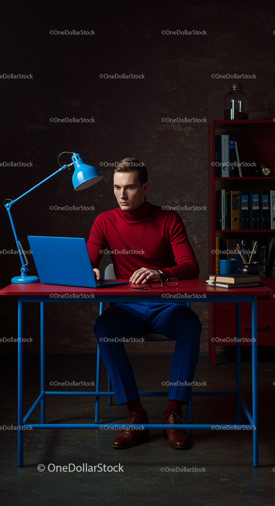 Focused Man in Red Turtleneck Working at Blue Desk