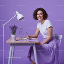 Happy Woman in Purple Dress Writing at a Modern Desk
