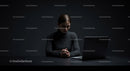 Contemplative Woman in Dark Workspace with Laptop