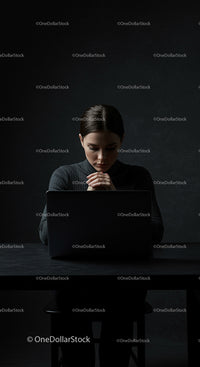Thoughtful Woman Working on Laptop in Dark Room
