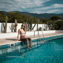 Smiling Woman Relaxing by a Pool with Cactus Garden