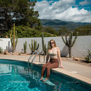 Woman Relaxing by Desert Pool with Cacti and Mountains