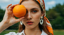 Fashionable Woman Holding Orange in Outdoor Setting