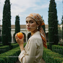 Elegant Woman Holding Orange in Mediterranean Garden