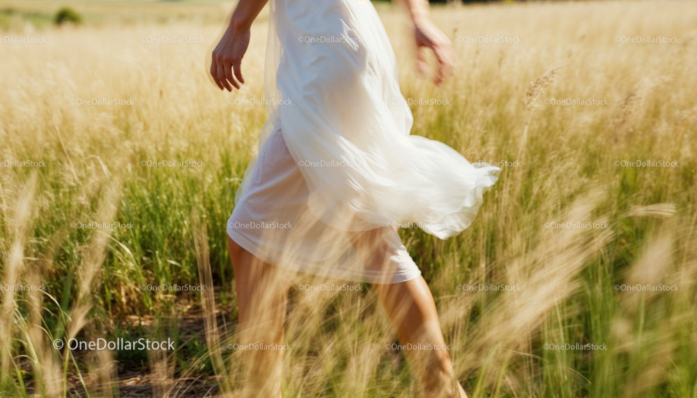 Woman in White Dress Walking Through Sunny Grass Field