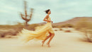Woman in Flowing Yellow Dress Running Through Desert