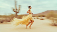 Woman in Flowing Yellow Dress Running Through Desert