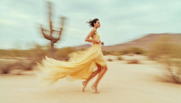 Woman in Flowing Yellow Dress Running Through Desert