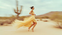 Woman in Flowing Yellow Dress Running Through Desert