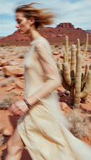 Woman in Flowing Dress Running through Desert Landscape