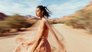 Elegant Woman in Flowing Peach Dress in Desert
