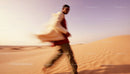 Man Walking Through Desert Dunes at Sunset