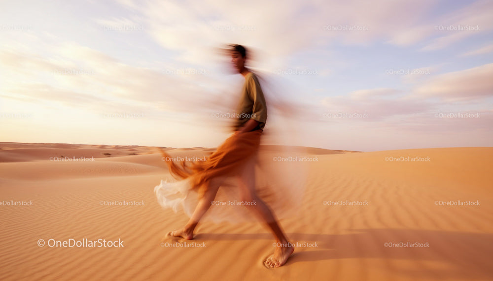 Blurred Figure Walking through Vast Desert Dunes
