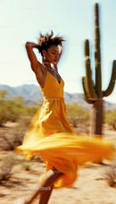 Carefree Woman Dancing in Yellow Dress in Desert