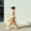Blurred Figure in Beige Walking in Urban Setting