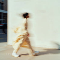 Blurred Figure in Beige Walking in Urban Setting