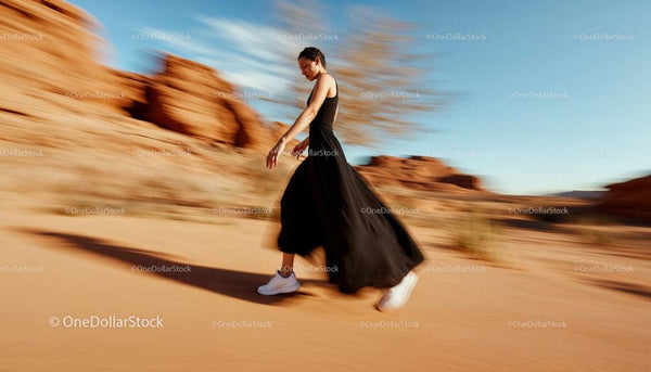 Elegant Woman in Black Dress Walking Through Desert Scene