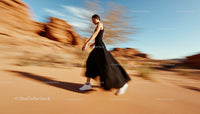Woman in Black Dress Walking Through Desert Landscape
