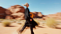 Stylish Woman in Motion Against Desert Landscape