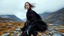 Woman in Black Coat Moving Through Windswept Landscape